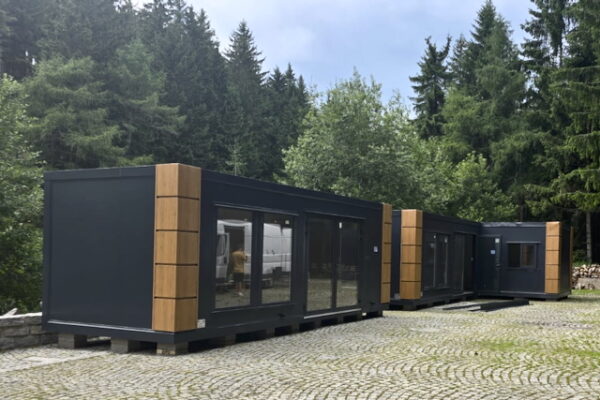 Bar przy kopalni uranu w Kowarach Nowoczesny bar kontenerowy przy wejściu do Kopalni Uranu w Kowarach, otoczony lasem i brukowanym placem